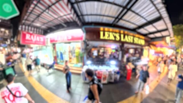 BANGKOK, THAILAND - NOV 2025 : Walking view of Sukhumvit street filled with neon lights of the nightlife entertainment district and urban traffic.
