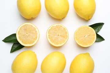 Fresh yellow lemons and green leaves on white background, flat lay
