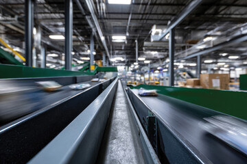 Obraz premium A dynamic view of moving conveyor belts inside a warehouse, signifying the fast-paced environment of logistics and goods handling in modern industry.