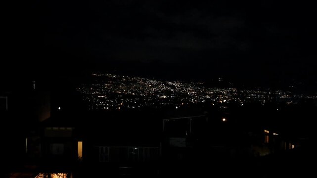 Handheld night view of Batu city&rsquo;s sparkling lights seen from a villa hillside, creating a dreamy bokeh effect that resembles glowing stars scattered across the landscape.