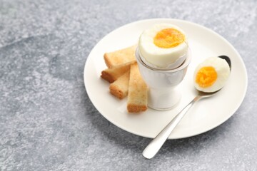Tasty breakfast with hard boiled egg and toasted bread on grey table, closeup. Space for text