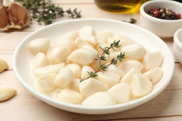 Pickled garlic and spices on wooden table, closeup