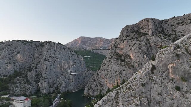 Drone flight above Mirabela Fortress and waving flag overlooking Omis and Adriatic coastline during golden sunset.