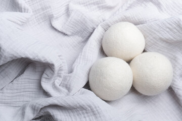 Wool laundry dryer balls arranged on a soft, textured white fabric background, showcasing their round shape and natural fibers in a clean, minimalist setting