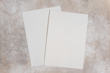Fototapeta premium Two sheets of deckle edge cotton watercolor paper placed on a textured surface, showcasing the natural fibers and unique edges of the paper