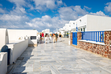 A wide pedestrian street terrace of whitewashed buildings with boutiques, cafes and shops in the hilltop town of Oia, Greece, the main tourist destination on the island of Santorini. © Kirk Fisher