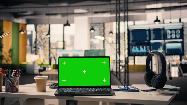 Laptop green screen mockup screen at empty office workstation, clean business environment with modern furniture and office supplies. Interior light, open space layout and no people present.
