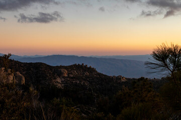 Obraz premium view of the mountains during sunset with the sky having a orange to blue gradient