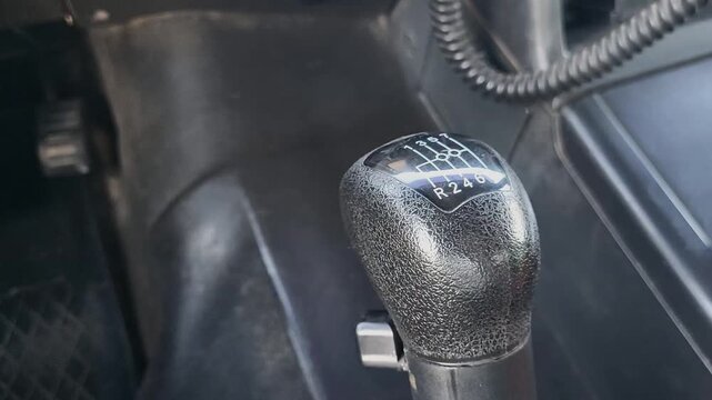 Close-up of a truck gear shift lever illuminated by soft dashboard lights, engine started and ready, interior of a heavy-duty vehicle cabin, focus on power and control, transportation or logistics ind