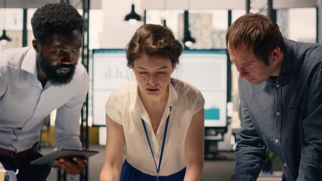 Diverse work team reviewing business intelligence reports and forecasting data in professional office workspace. Team collaboration based on objectives and data analysis in startup environment.