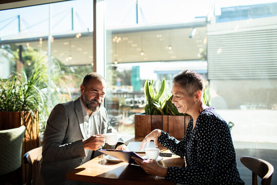 Two colleagues discussing business over coffee in a sunny cafe