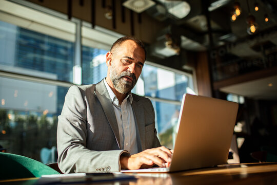 Mature businessman working on laptop in cafe