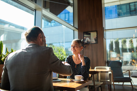 Two business people shaking hands in modern cafe meeting