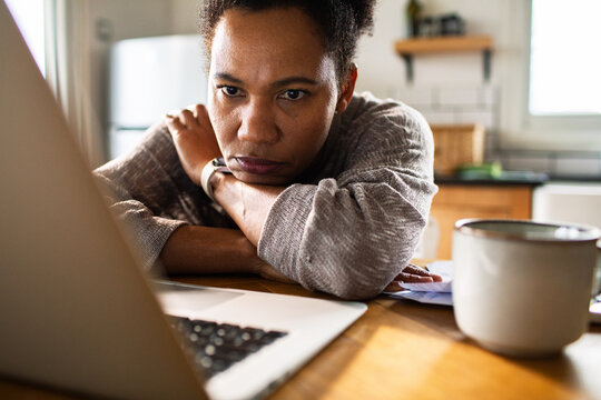 Stressed woman looking at laptop while paying bills at home