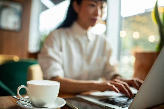 Woman working on laptop at cafe with coffee