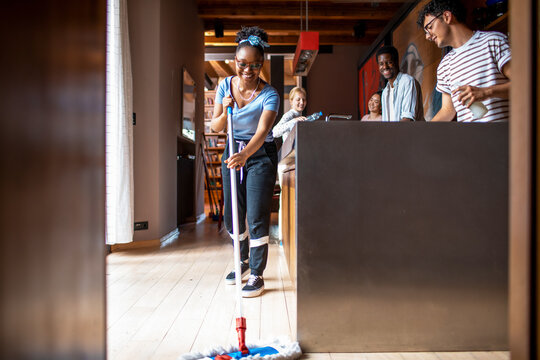 Young roommates mopping and cleaning kitchen at home