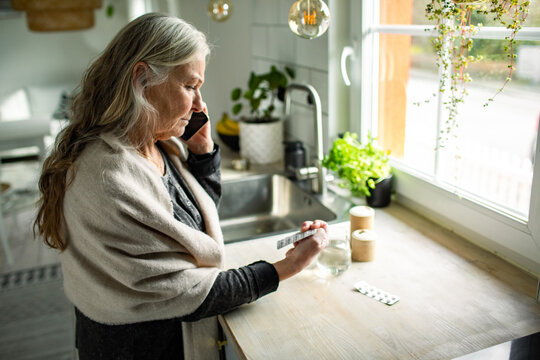 Senior woman calling doctor about medication at home kitchen