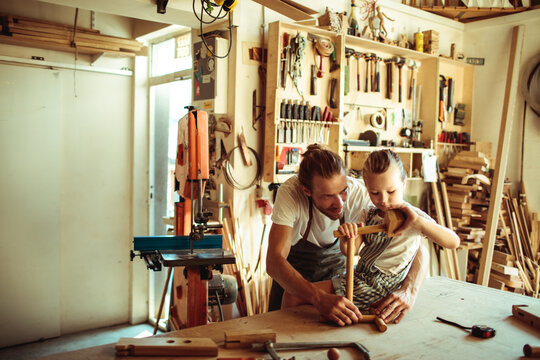 Father and daughter building wooden toy in home workshop
