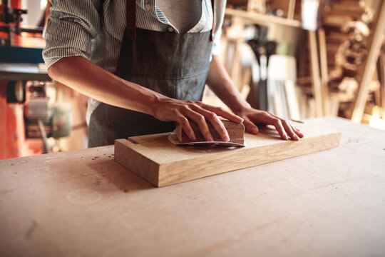 Woodworker sanding wooden board in workshop