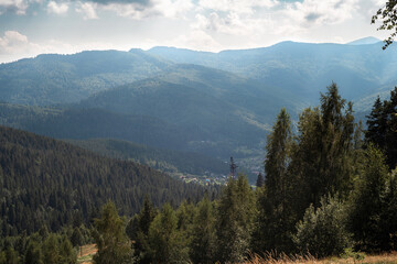 Obraz premium Mountain Forest Valley with Hills and Dramatic Cloudy Sky