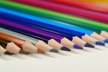 New wooden colored pencils of rainbow colors, perfectly sharpened, lie on table