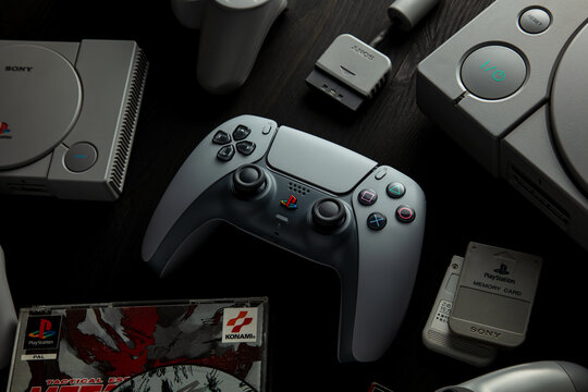 February 17, 2026, Odessa, Ukraine.  A gray DualSense 30th Anniversary PlayStation controller sits on a wooden background surrounded by PS1 consoles and accessories.
