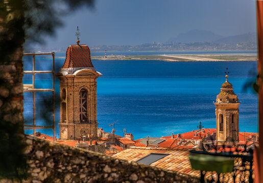 Bell towers rise over terracotta roofs above the Mediterranean sea, Nice, France