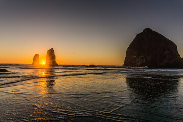 The sun is setting over the ocean, casting a warm glow on the water © ExploringandLiving