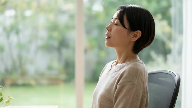 Posture correction ergonomic workspace woman practicing relaxation and comfort sitting calmly modern office chair with computer and plant near window