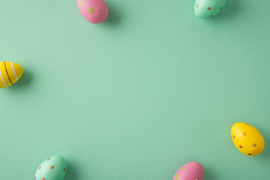 Happy Easter celebration and greeting featuring pastel decorated eggs arranged around a mint green background with copyspace for cards posters or social media promotion