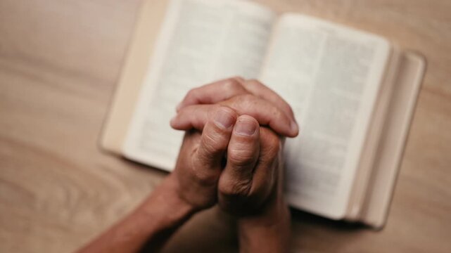 Old man hands clasped prayer with Holy Bible for Christian faith, spirituality, worship, devotion, hope, and religious belief, prayer time in church, trust in God, and spiritual guidance.