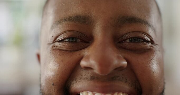 African American man starting neutral, smiling, laughing at home by window plant showing teeth
