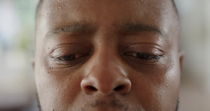 Middle-aged man lowering gaze, blinking, reopening eyes after glancing at off-camera window in room