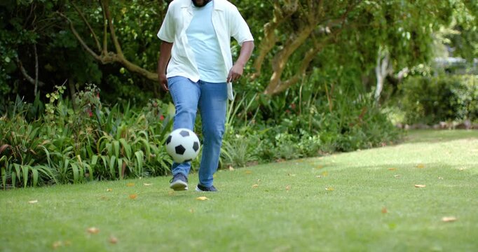 Man is walking onto grassy yard from left, approaching black-white soccer ball, practicing control