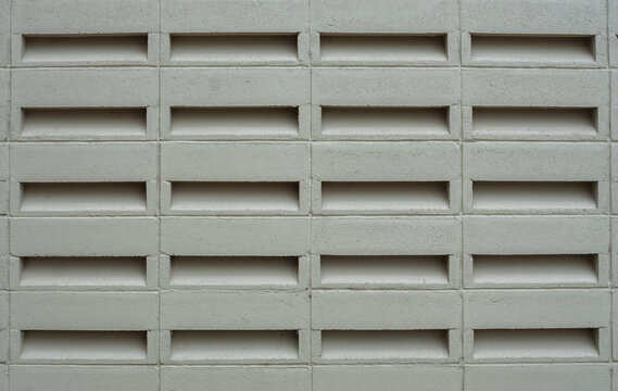 Close-up of a grey concrete breezeblock wall. The repeating rectangular ventilation blocks create a geometric pattern and texture, perfect for modern tropical exterior design backgrounds.