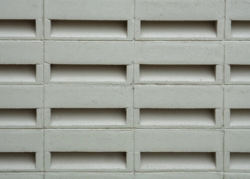 Close-up of a grey concrete breezeblock wall. The repeating rectangular ventilation blocks create a geometric pattern and texture, perfect for modern tropical exterior design backgrounds.