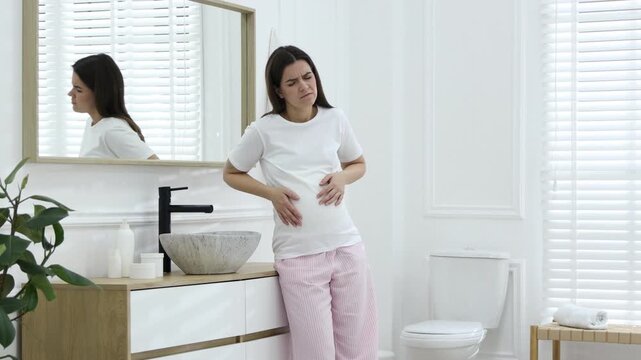 Pregnant woman suffering from nausea over sink in bathroom. Toxicosis during pregnancy
