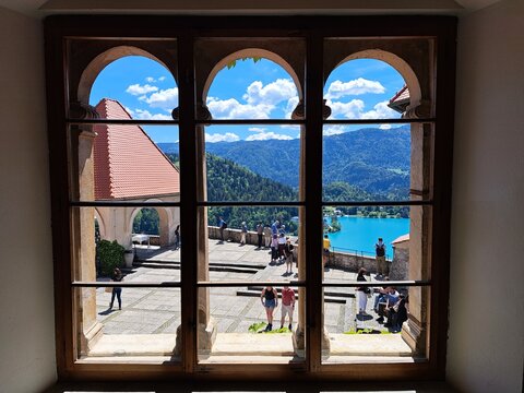 Triple arched window view of Bled Castle courtyard and lake