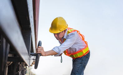 Railway maintenance engineer inspecting freight car undercarriage on track, Engineer performing preventive maintenance on railway freight car, Industrial worker checking train wheel and suspension