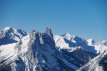 Fototapeta premium Jagged snow-covered mountain peaks against a clear blue sky in the Canadian Rockies.
