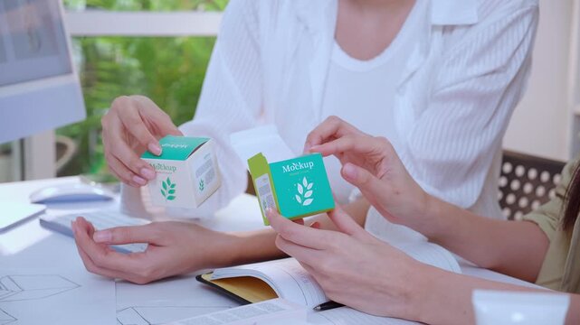 Hand holding cosmetic packaging mockup box, graphic designer and development branding project, sketch and layout artwork, business startup planning creative for skincare product label advertising.