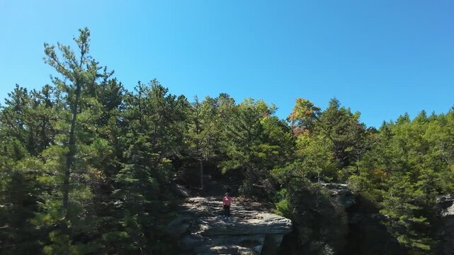 Hiker Overlooking Mountains. Climber Views Distant Mountain Range. Adventurer Gazes At Vast Rocky Landscape. Wanderer Stands On Cliff Surveying Extensive Mountain Vistas From Above
