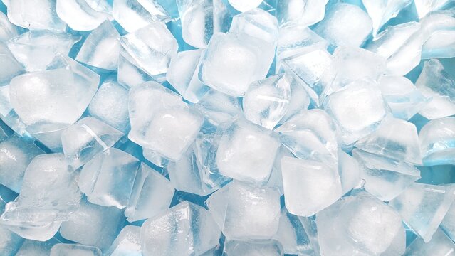 Top view of fresh ice cubes on blue background. Crystal clear ice cube texture with cold feeling. Crushed ice pieces creating a cool frozen background.