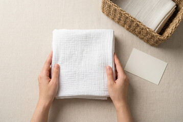 Hands Holding Folded White Muslin Cloth On Linen Background