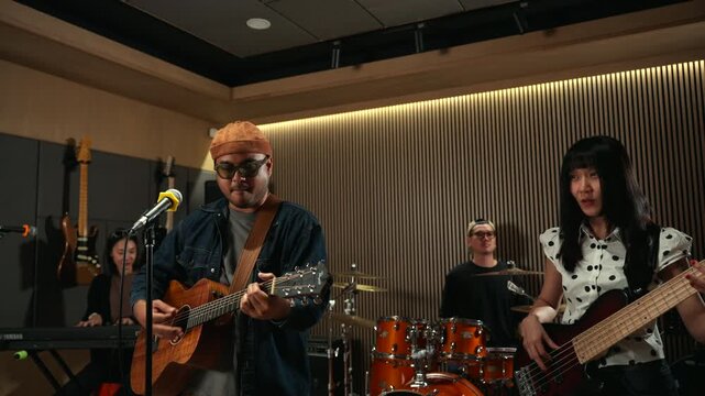 Band musicians performing live professional in recording studio, practicing rehearsal session with vocals bassist and drummer teamwork, music production creative and energetic live performance.
