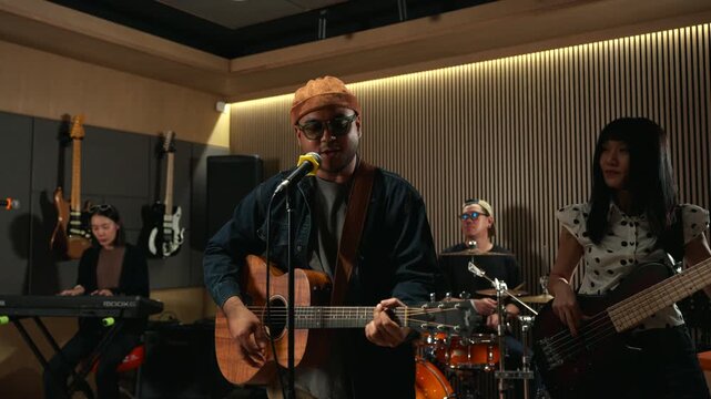 Band musicians performing live professional in recording studio, practicing rehearsal session with vocals bassist and drummer teamwork, music production creative and energetic live performance.
