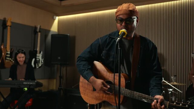 Band musicians performing live professional in recording studio, practicing rehearsal session with vocals bassist and drummer teamwork, music production creative and energetic live performance.

