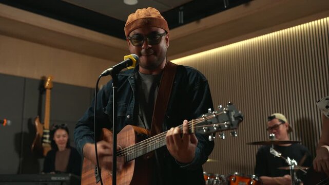 Band musicians performing live professional in recording studio, practicing rehearsal session with vocals bassist and drummer teamwork, music production creative and energetic live performance.
