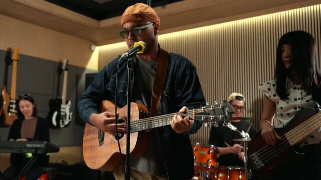 Band musicians performing live professional in recording studio, practicing rehearsal session with vocals bassist and drummer teamwork, music production creative and energetic live performance.
