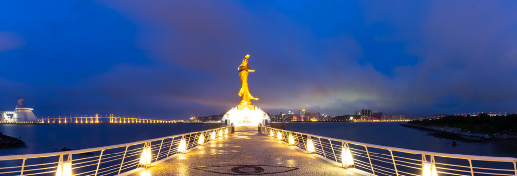Kun Iam Ecumenical Centre illuminated at twilight over waterfront.